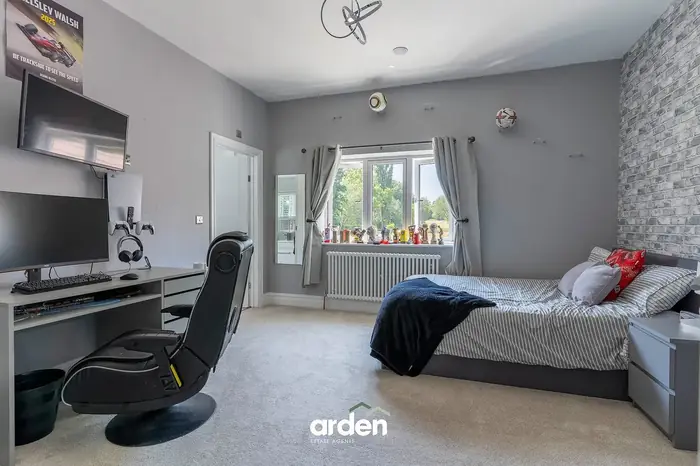 Bedroom with a brick effect feature wall and a desk