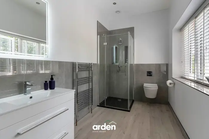 Shower room with a wall hung WC and grey tile